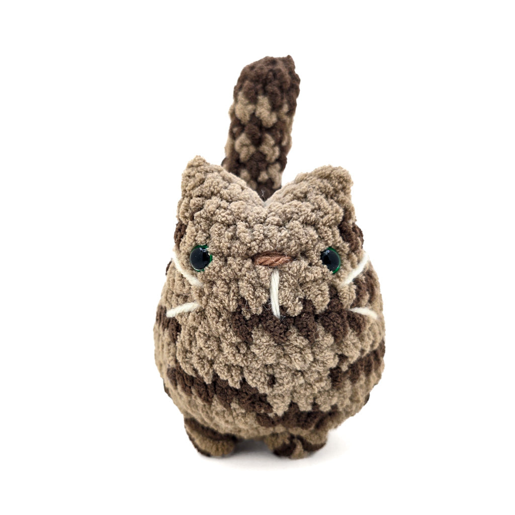 A hand-crocheted brown tabby cat plush toy made with soft yarn.