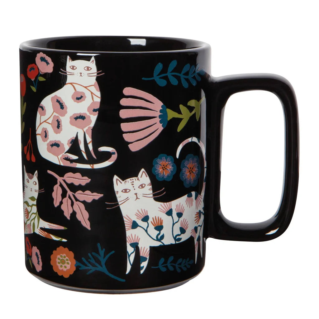 Black mug with colorful cat and floral design on a white background