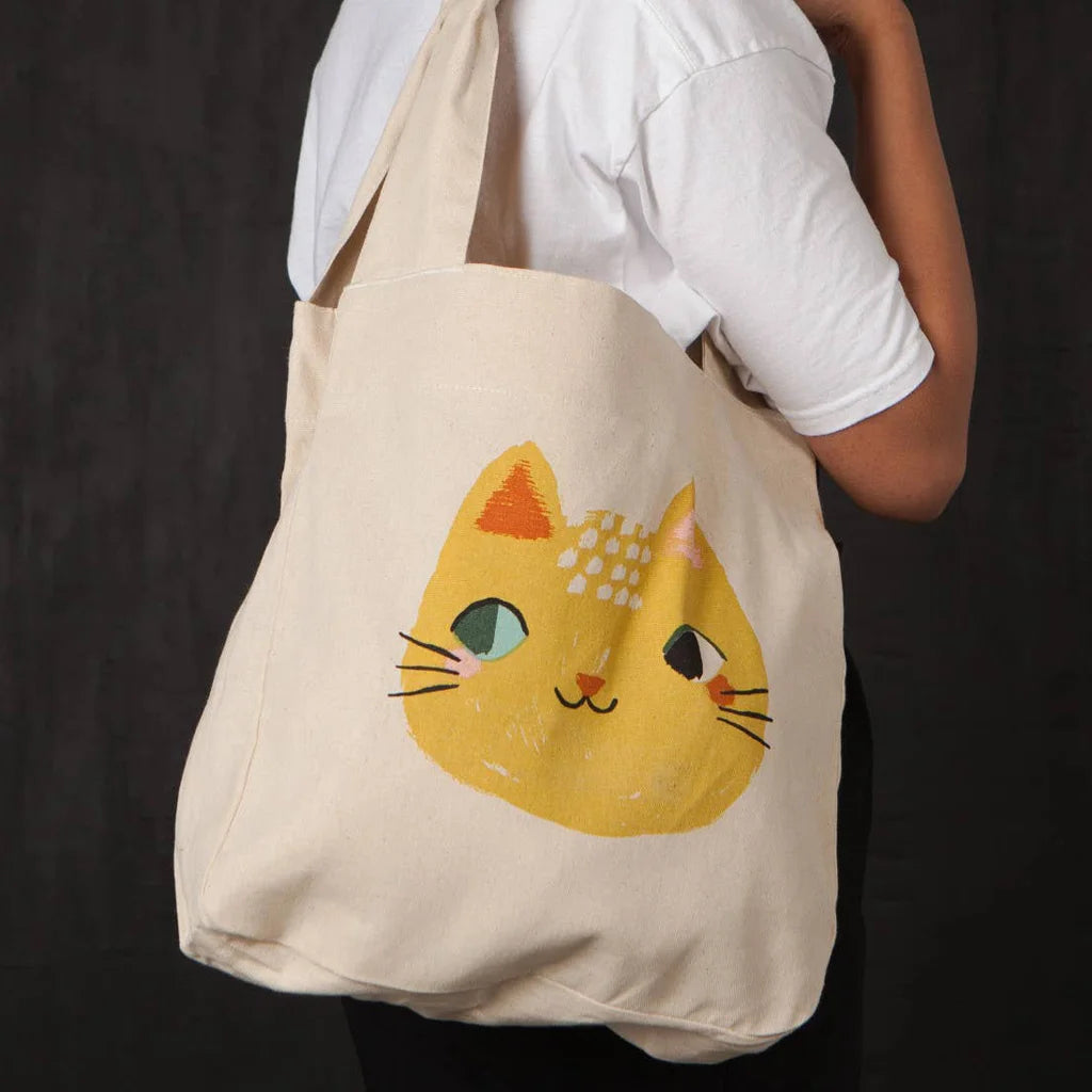 Natural cotton tote bag with a yellow cat face design on a white background