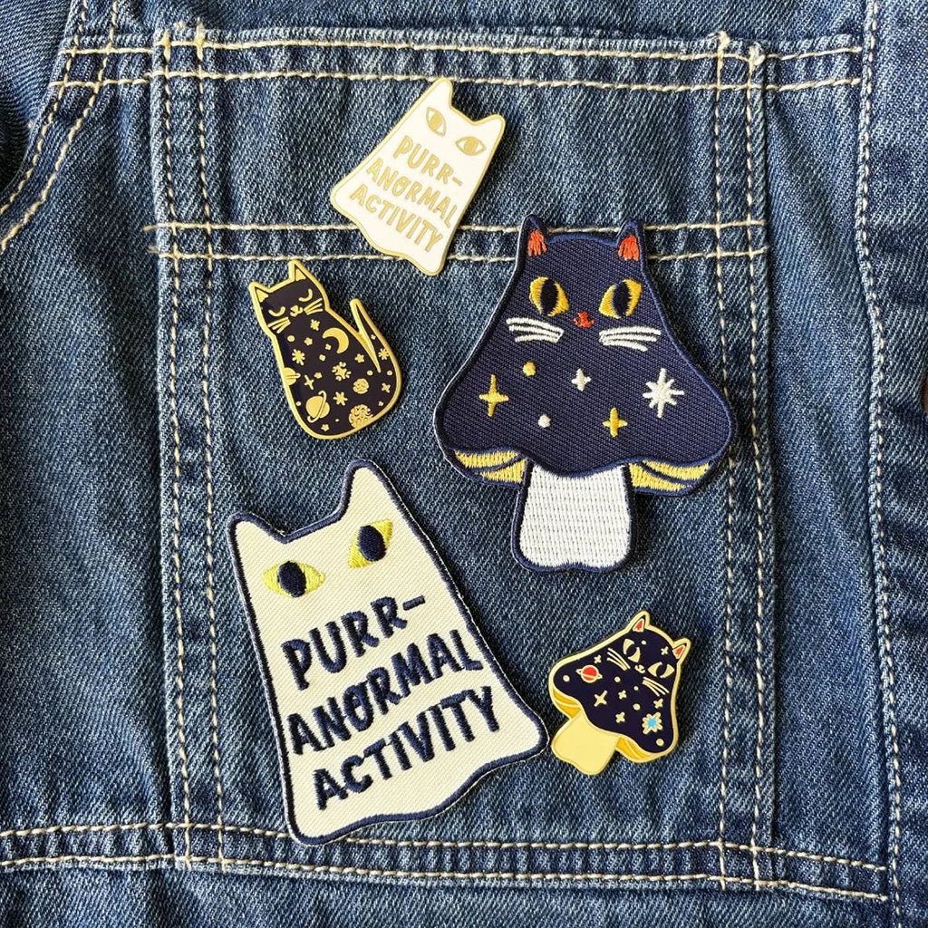 Embroidered patch of a cat ghost design and text 'Purr-Anormal Activity' on a beige background.